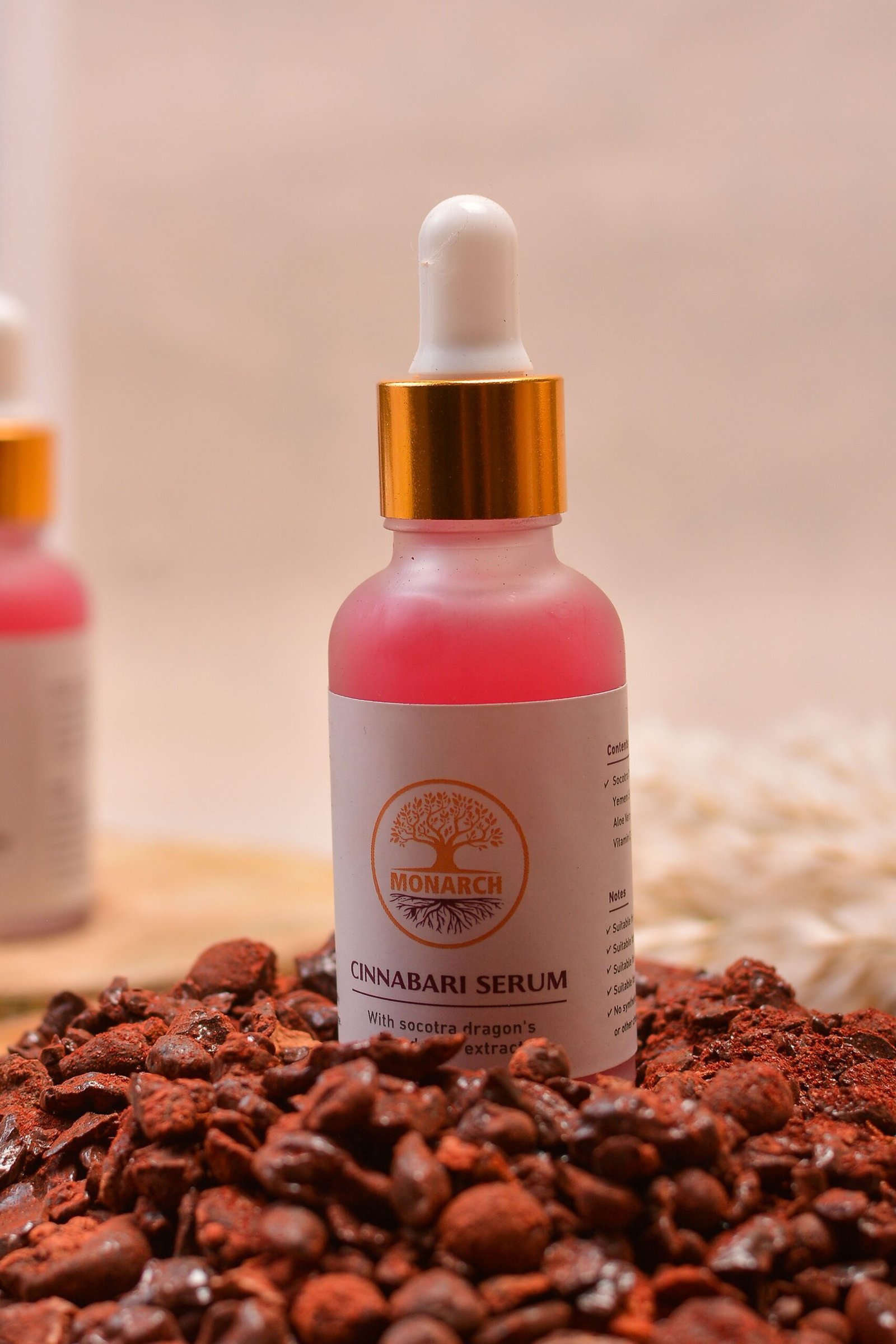 Close-up of Cinnabari Serum bottle surrounded by raw cinnabar stones for skincare.