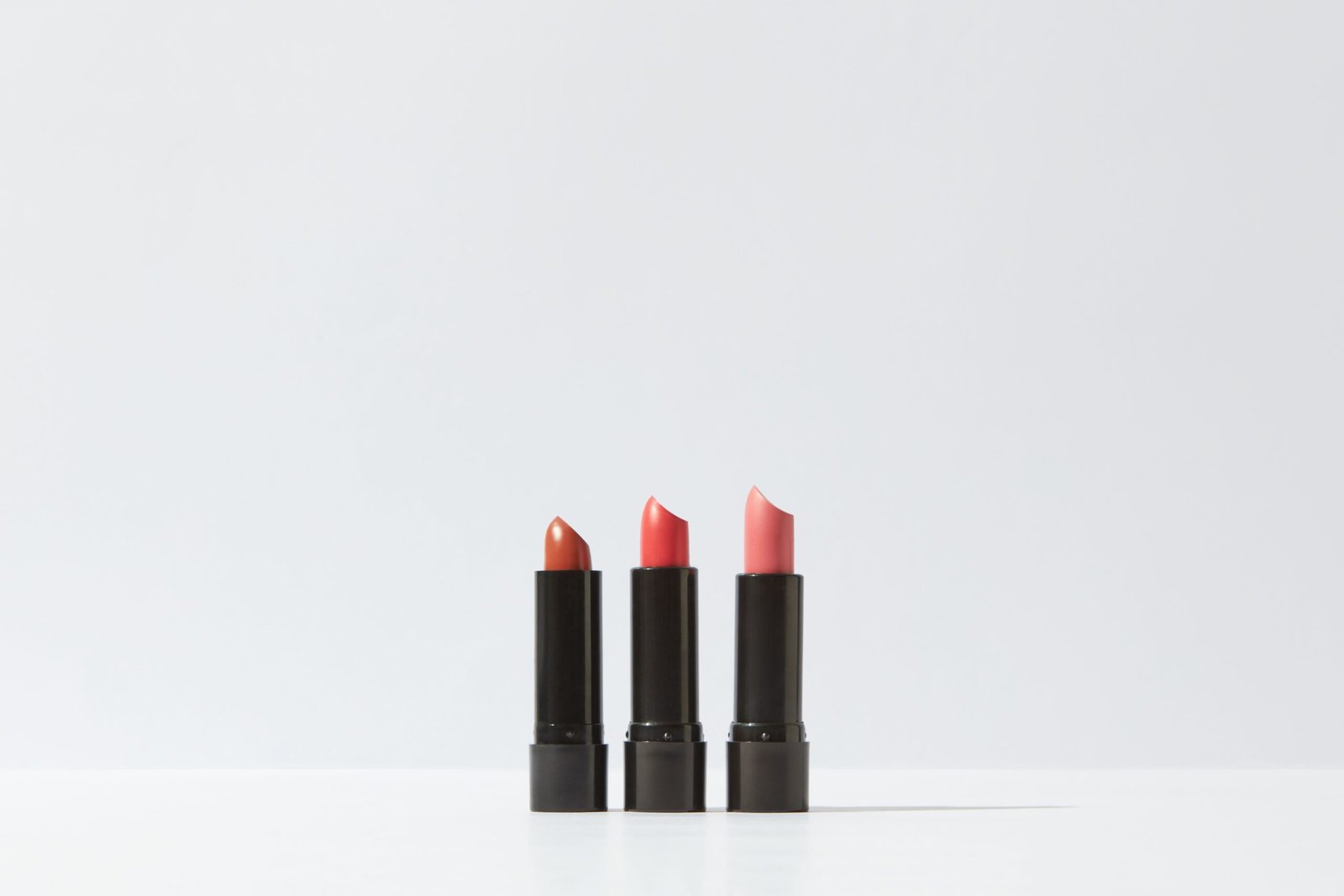 A minimalist display of three lipsticks on a white background, perfect for cosmetic themes.